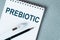 The text PREBIOTIC is written on notepad with a black pen and electronic thermometre on it on a blue background. Medical concept