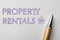 Text Property Rentals and pen on white paper, top view