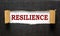 The text `resilience` appearing behind torn black paper