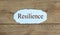 Text `resilience` on the piece of paper. Beautiful wooden background. Business concept
