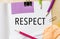Text RESPECT on a white note background with pencils, stickers and paper clips. Business concept