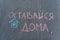 Text in Russian `Stay at home` written in chalk on the asphalt