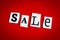 Text SALE on red background of cut out letters. Message on poster, card. Inscription on banner. Shopping concept. Single word, adv