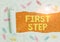 Text sign showing First Step. Conceptual photo The first of a series of actions Act of starting something Paper clip and