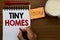 Text sign showing Tiny Homes. Conceptual photo houses contain one room only or two and small entrance Cheap Man holding marker not