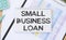 text SMALL BUSINESS LOAN , next to magnifier and pen, the background is graphics