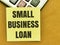 Text SMALL BUSINESS LOAN written on yellow paper note on calculator.