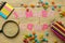 Text SUMMER CAMP of multicolored paper letters and colored pencils and candies on a natural wooden background. top view. flat lay