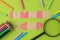 Text SUMMER CAMP of multicolored paper letters and crayons, pencils on a bright green background. top view. flat lay