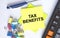 Text Tax Benefits on yellow stickers with calculator, blue pen and paper clips