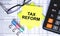 Text Tax Reform on yellow stickers with calculator, eyeglasses and paper clips