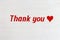 Text thank you and red colored heart on white wooden background with copy space. Words of gratitude and expressions of