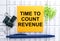 Text Time To Count Revenue on financial tables with pen and paper clips