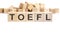 text TOEFL made of wooden cubes and different words on white background