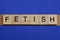 Text the word fetish from gray wooden small letters