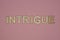 Text the word intrigue from gray wooden small letters