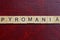 Text the word pyromania from gray wooden small letters