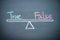 Text word true and false balance on seesaw drawing writing on chalkboard or blackboard background. Concept of true and false