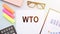 The text WTO - World Trade Organization, on office desk with calculator, markers, glasses and financial charts