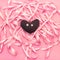 Textile toy heart on the background of a Coil of decorative satin ribbons of pink color.