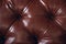 The texture of the background is a close-up of brown genuine leather, upholstered furniture in retro Chesterfield style