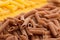 Texture background of raw italian pasta penne rigate made of buckwheat flour.