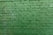 The texture of the brick wall of many rows of bricks painted in green color. St Patricks Day dirty green brick wall background.