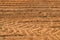 The texture of the brown earth of the sand road with traces of the tire treads of the tractor`s car tires. The background