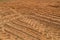 The texture of the brown earth of the sand road with traces of the tire treads of the tractor`s car tires. The background