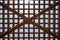 Texture of a brown wooden abstract lattice with square cells with holes from boards of log beams arranged vertically horizontally