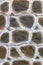 The texture of a concrete wall in the style of a swamp-colored snake skin, paved with large cobblestones. Close-up