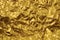 Texture of crumpled golden yellow foil with dents close-up