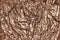 Texture of crumpled sheet of bronze foil, background closeup. Structure of creased shiny wrapping paper.