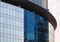 Texture of the facade of glass building of round shape with the reflection sky in it.