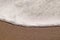 Texture of the foamed wave of the sea on a sandy beach, close up with copy space.