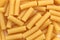 Texture of golden brown pasta in the form of pipes