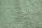 Texture of green reflective rough concrete wall. Shiny hilly green wall background close-up. Painted rough green cement wall. The