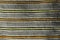 Texture of handmade carpet made on hand-loom, pattern of yellow, orange and black vertical lines dividing grey vertical fields