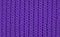 Texture of knitted wool fabric with of a lilac color with pattern. Top view. Close-up. Selective focus