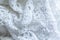 The texture of lace on a white background. Closeup of rippled white fabric. Abstract background of luxurious cloth for a wedding d