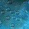 Texture. Large drops of rain with blue halo and silhouettes of flowing raindrops are located on the turquoise background.