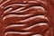 Texture of liquid molten chocolate, wave pattern. Shiny silky chocolate background