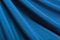 He texture of a luxurious smooth fabric in blue with folds and waves. Blue fabric, material