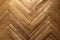 Texture of obsolete scratched lacquered wood parquet laid out in the shape of a herringbone, close-up
