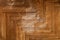 Texture of obsolete scratched lacquered wood parquet with a stain of erased lacquer coating in the center, close-up