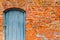 The texture of the old ancient medieval antique solid wooden thick door against the background of a stone wall of red brick