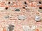 The texture of the old ancient medieval antique stone hard peeling cracked brick wall of rectangular red clay bricks large stones