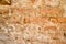 The texture of the old ancient medieval antique sturdy stone peeling scratched wall of rectangular red orange bright brick