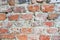 The texture of the old ancient medieval antique sturdy stone peeling scratched wall of rectangular red orange bright brick