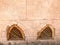 Texture of the old ancient yellow stone strong wall with windows of wooden shutters from below in the Arab Islamic Islamic warm tr
